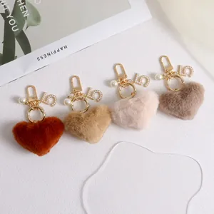 Detail of plush heart keychains in four earth tones with pearl and number five charms
