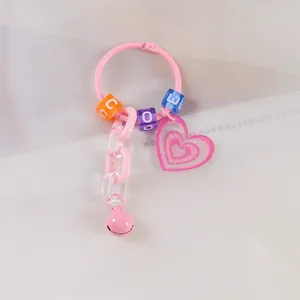 Dettaglio portachiavi rosa Y2K con cuore glitterato, perline con lettere e campanellino