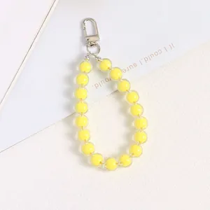 Detailed macro view of yellow acrylic bead charm with glossy silver lobster clasp and key ring