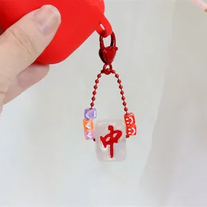 Red Mahjong 'Hong Zhong' keychain charm with colorful beads on a red earphone case