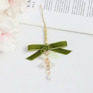 Detalle de lazo de terciopelo verde oliva con flores de lirio de los valles y perlas