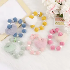 Détail de bracelets en peluche avec cœur et perles en plusieurs couleurs sur fond blanc