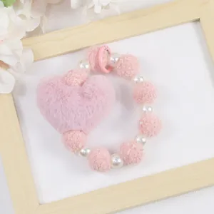 Détail d'un porte-clés cœur en peluche rose avec perles blanches et texture douce