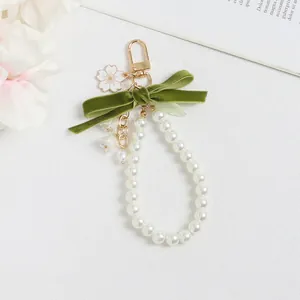 Detalle del llavero de lirio de los valles con cinta de terciopelo y cadena de perlas