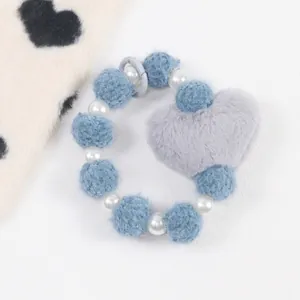 Détail du bracelet en peluche avec boules bleues, perles blanches et charme de cœur gris