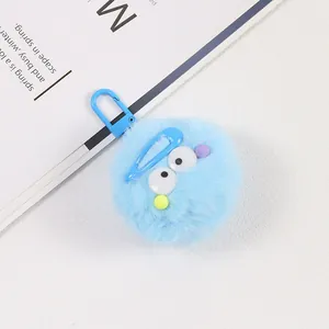 Détail d'un porte-clés en peluche bleue avec de grands yeux et une pince à cheveux