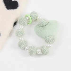 Détail de bracelet en peluche vert clair avec perles et pendentif en forme de cœur