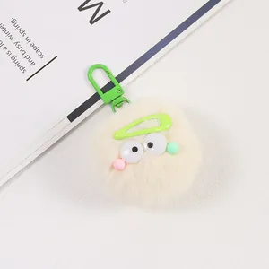Gros plan d'un porte-clés en peluche crème avec de grands yeux et un mousqueton vert