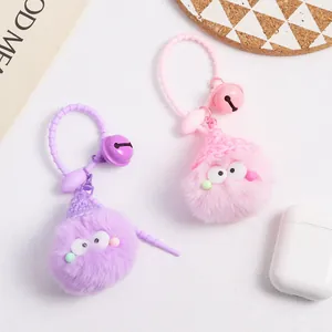 Detail of plush pompom charms featuring knit hats and bells on a white background