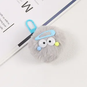 Gros plan d'un porte-clés monstre en peluche grise avec un crochet bleu pastel