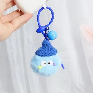 Blue fuzzy pom pom keychain with knit hat and bell on earphone case detail view