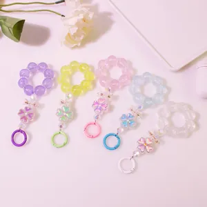 Dettaglio di portachiavi con perline colorate, fiori di mughetto in resina e clip in metallo