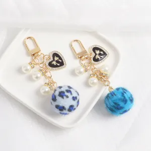 Détail du porte-clés pompon léopard avec pendentif en forme de cœur et perles blanches