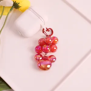 Iridescent purple bead charm with red heart clasp on a white headphone case