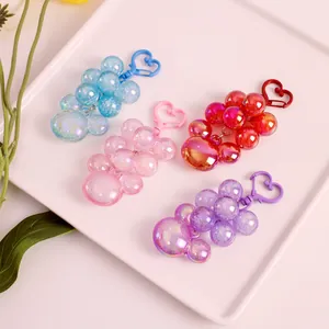 Close-up of four colorful laser bubble grape keychains in a white decorative tray