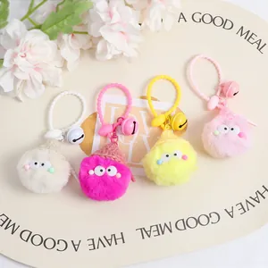 Detail view of colorful plush pompom keychains with knit hats and small bells for bags