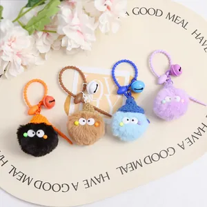 Detail of furry monster keychains with knitted hats and bells on a display mat