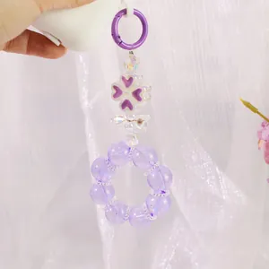 Dettaglio del portachiavi di perline viola con ciondoli a quadrifoglio e fiocco su tulle