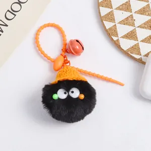 Detail shot of black pom-pom keychain with orange knit hat and bell on bag
