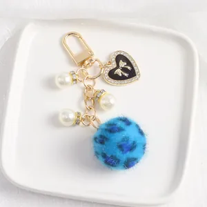 Détail de pompon en peluche léopard bleu avec perles et pendentif coeur de luxe