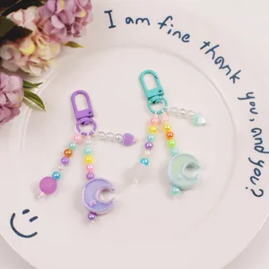 Macro view of colorful macaron beaded keychains with moon and heart charms on a white plate