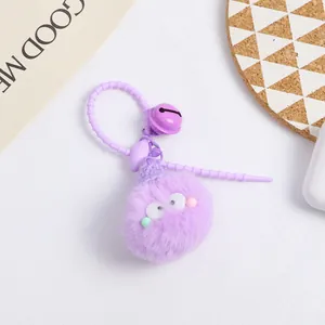 Macro detail of a purple plush keychain ball with big eyes, bell, and silicone lanyard
