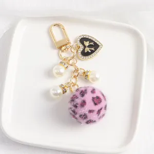 Détail du pendentif cœur avec cristaux, perles et pompon en peluche rose à motif léopard