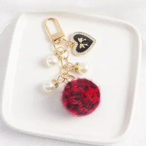 Détail du porte-clés pompon léopard avec pendentif en cœur et perles blanches