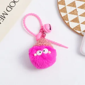 Macro detail of pink plush keychain with knit hat, cute eyes, and pink bell ornament