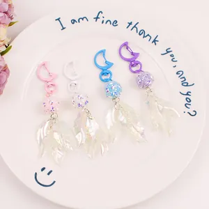 Detail of colorful leaf keychain set with moon-shaped clasps and glitter beads in a dish