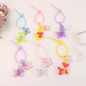 Colorful balloon dog keychains with acrylic charms and beads on minimalist background