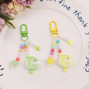 Detail of colorful moon and star beaded keychains in green and yellow on a white plate