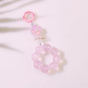 Dettaglio di un portachiavi a quadrifoglio rosa con catena di perline e ciondoli lucidi