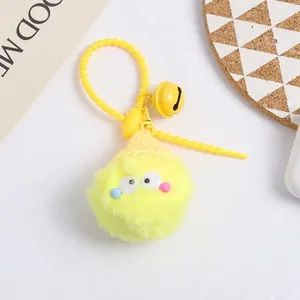 Detail of yellow faux fur pom pom keychain with cute eyes, golden bell and woven hat part
