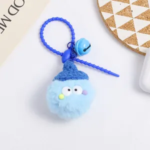 Close-up of a light blue plush ball keychain with a knitted hat, bell and beads