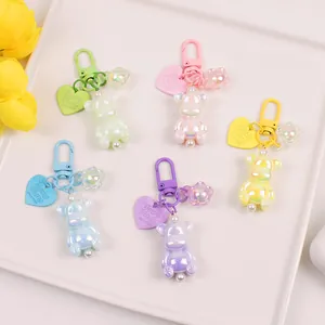 Detailed view of colorful iridescent resin bear keychains in five pastel shades and charms