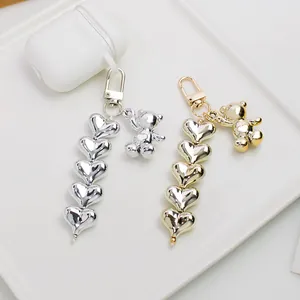 Silver and gold metallic bear charms with stacked heart chains on white background