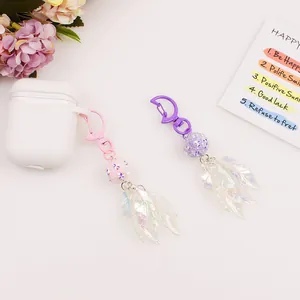 Detail of colorful laser leaf keychain charms attached to a white headphone case