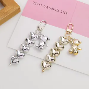 Detail of silver and gold heart pendant keychains with metallic bear charms on display