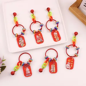 Close-up of 6 red Chinese New Year rabbit keychains with lucky charms and acrylic tags