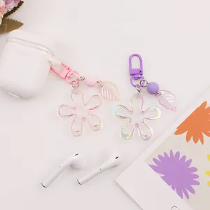 Detail showing pink and purple floral acrylic keychains with iridescent petals on desk