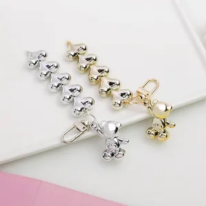 Detail of silver and gold metal bear charms with heart link chains and lobster clasps