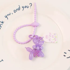 Détail d'un porte-clés chien ballon violet avec une sangle flexible et un petit charme