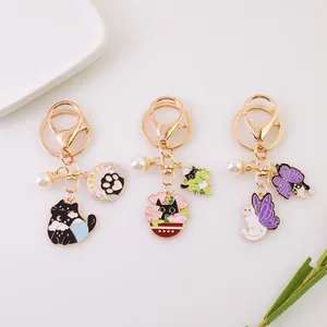Three cat-themed enamel keychains with star and cloud charms in a decorative setting