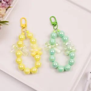 Macro detail of cute bear beaded keychain in yellow and mint green with metallic charms