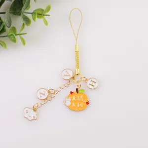 Détail d'un porte-clés orange en émail avec cordelette dorée et illustrations de chat