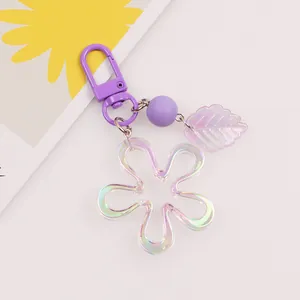 Close-up of a purple acrylic flower keychain with a metallic D-ring and iridescent leaf