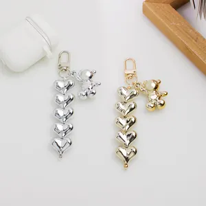 Detailed view of silver and gold metal bear pendants with heart-shaped beads for bags