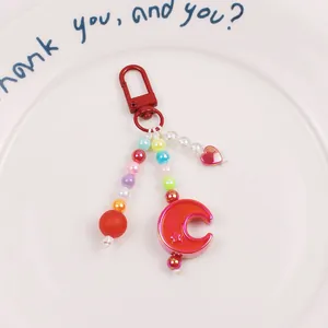 Macro detail of colorful resin beads and gradient moon pendant on a beaded keychain