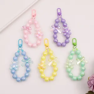 Colorful beaded keychains featuring macaron bears and transparent bows on white background
